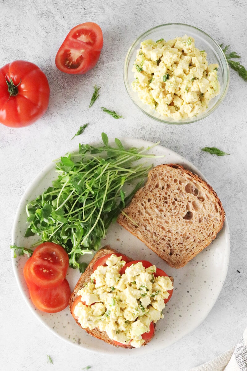 Vegan Egg Salad on a plate with arugula and tomatoes.