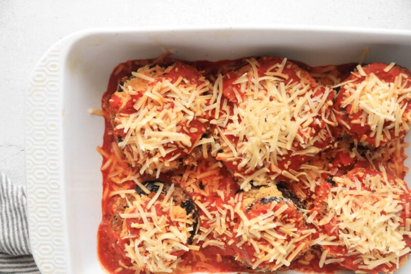 Fully cooked eggplant parmesan in a white casserole dish