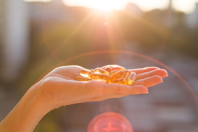 Woman's hand holding omega-3 supplements in sunlight