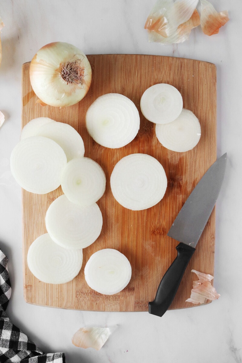 Using a large chef's knife to cut onions into 1/4 inch slices.