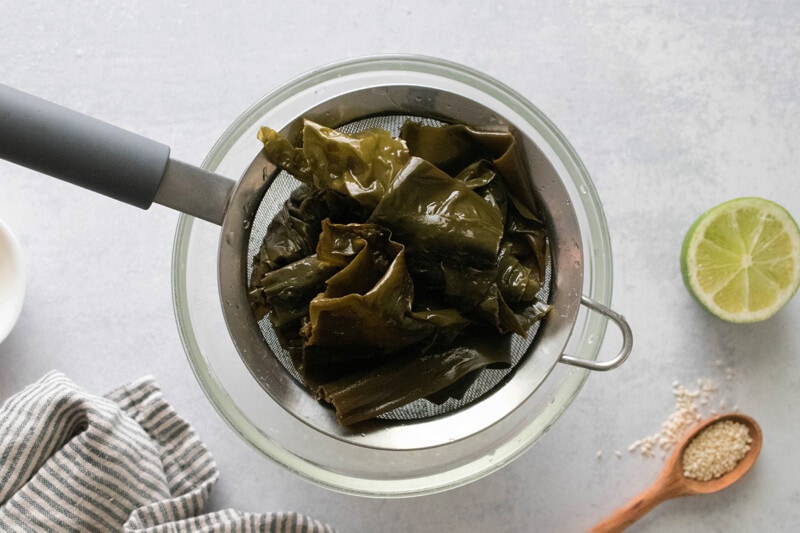 Draining seaweed in a strainer.
