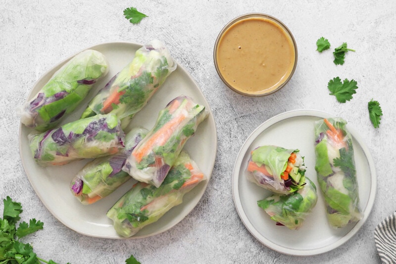 Completed vegan spring rolls on a plate, served with a dish of peanut sauce.