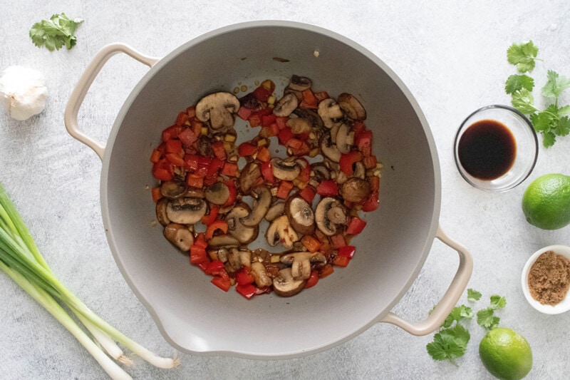 Cooking mushrooms and red bell peppers with Thai chili paste.