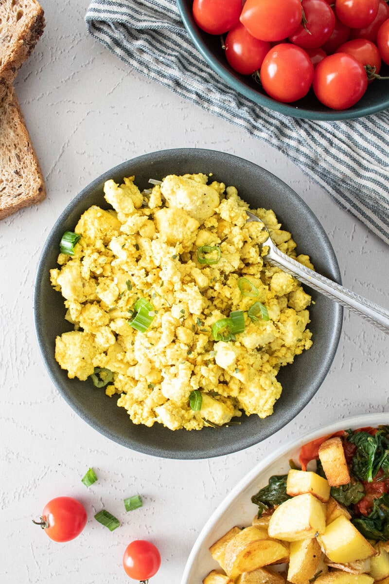 Vegan tofu scramble topped with fresh green onions in a bowl.