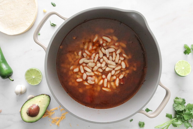 A large pot with broth, beans, corn, and canned tomatoes added.