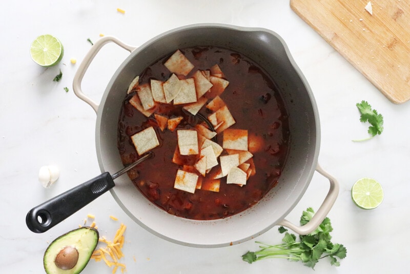 Vegan tortilla soup in a large pot with the tortilla squares added.