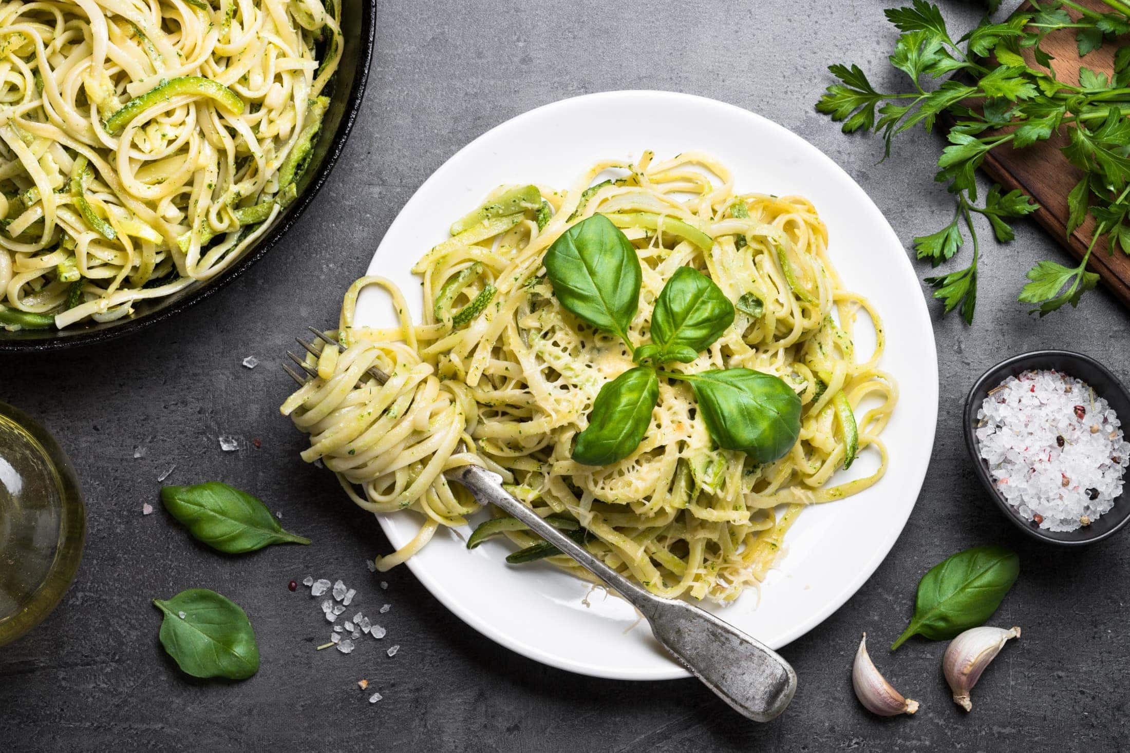 Vegetarian pasta and basil leaves on a white plate with dark background