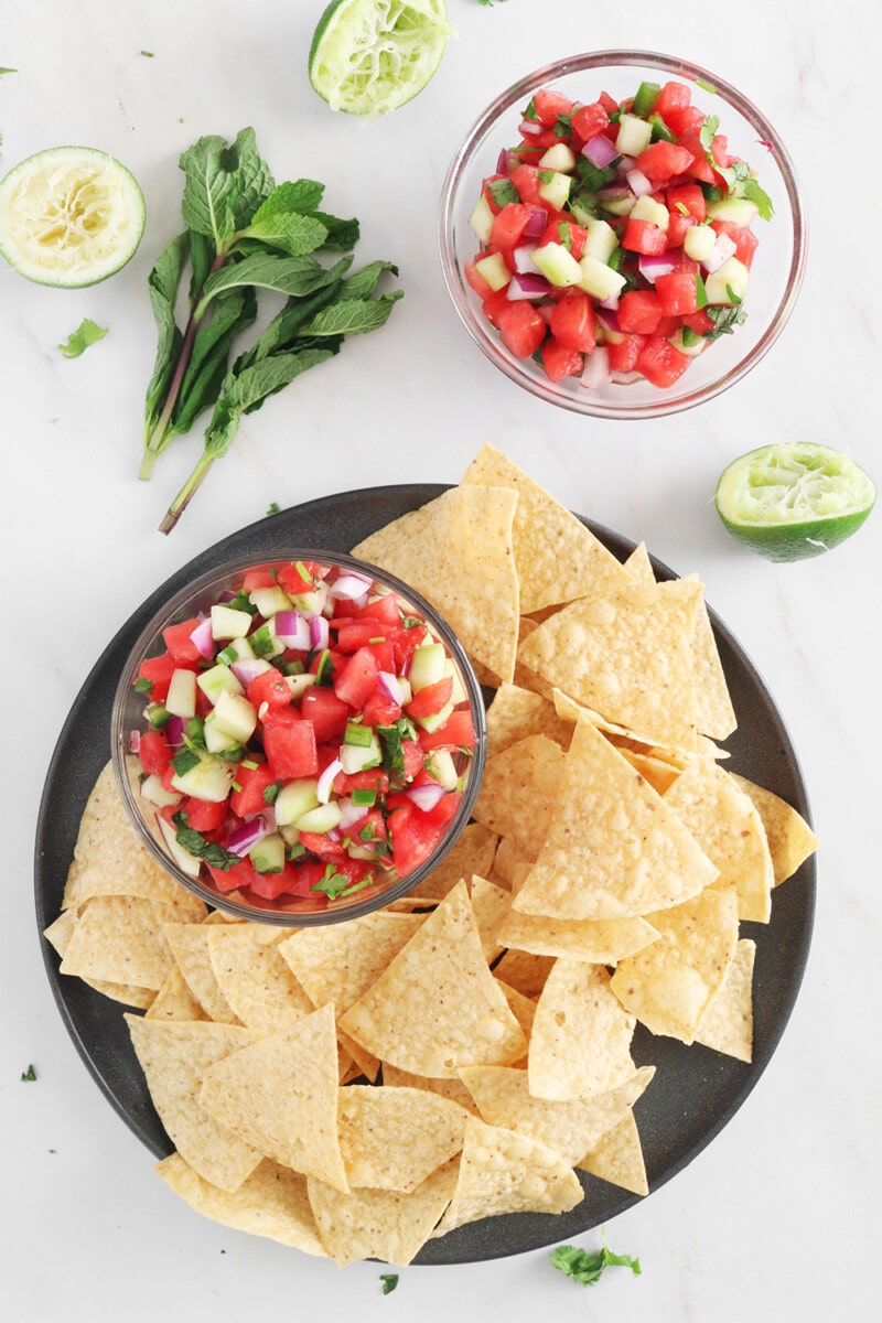 Watermelon Salsa with tortilla chips on a black plate.