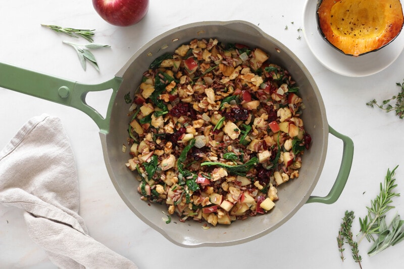 Wild rice with apples, tempeh, kale, cranberries, and walnuts in a pan.