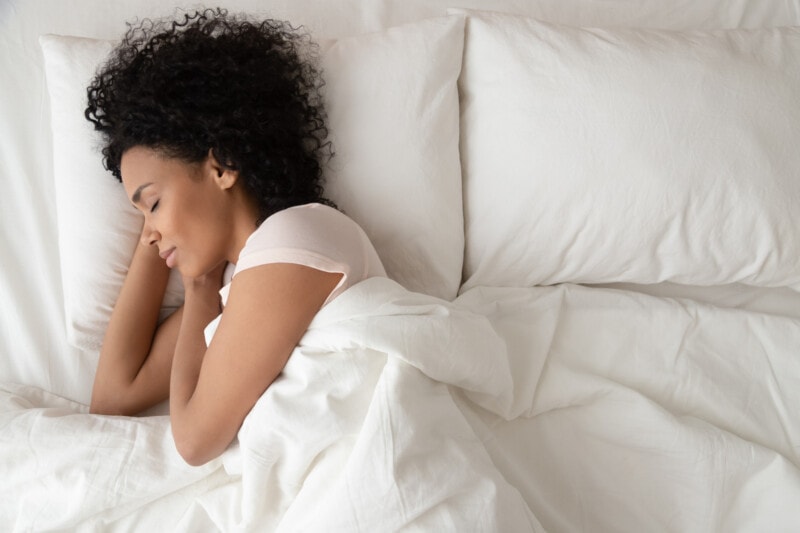 African American woman sleeping on white sheets